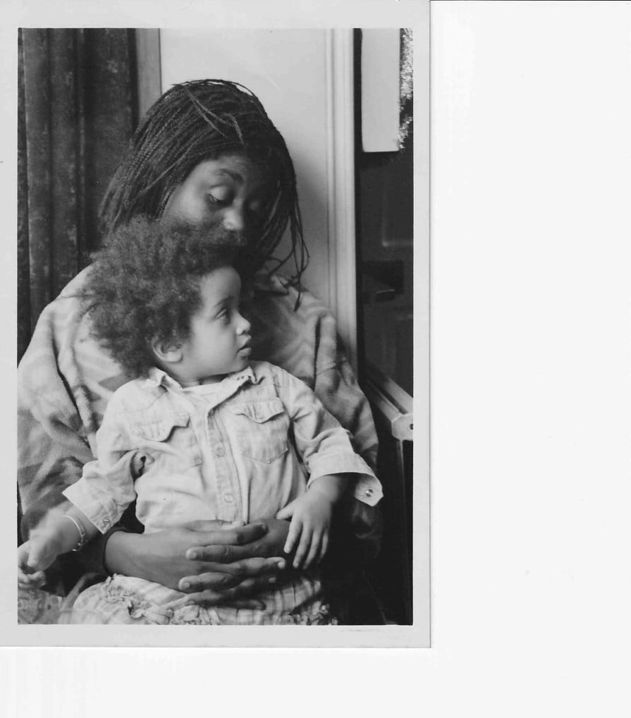 A black and white photo of Zakia Sewell at a young age, being held by her mother