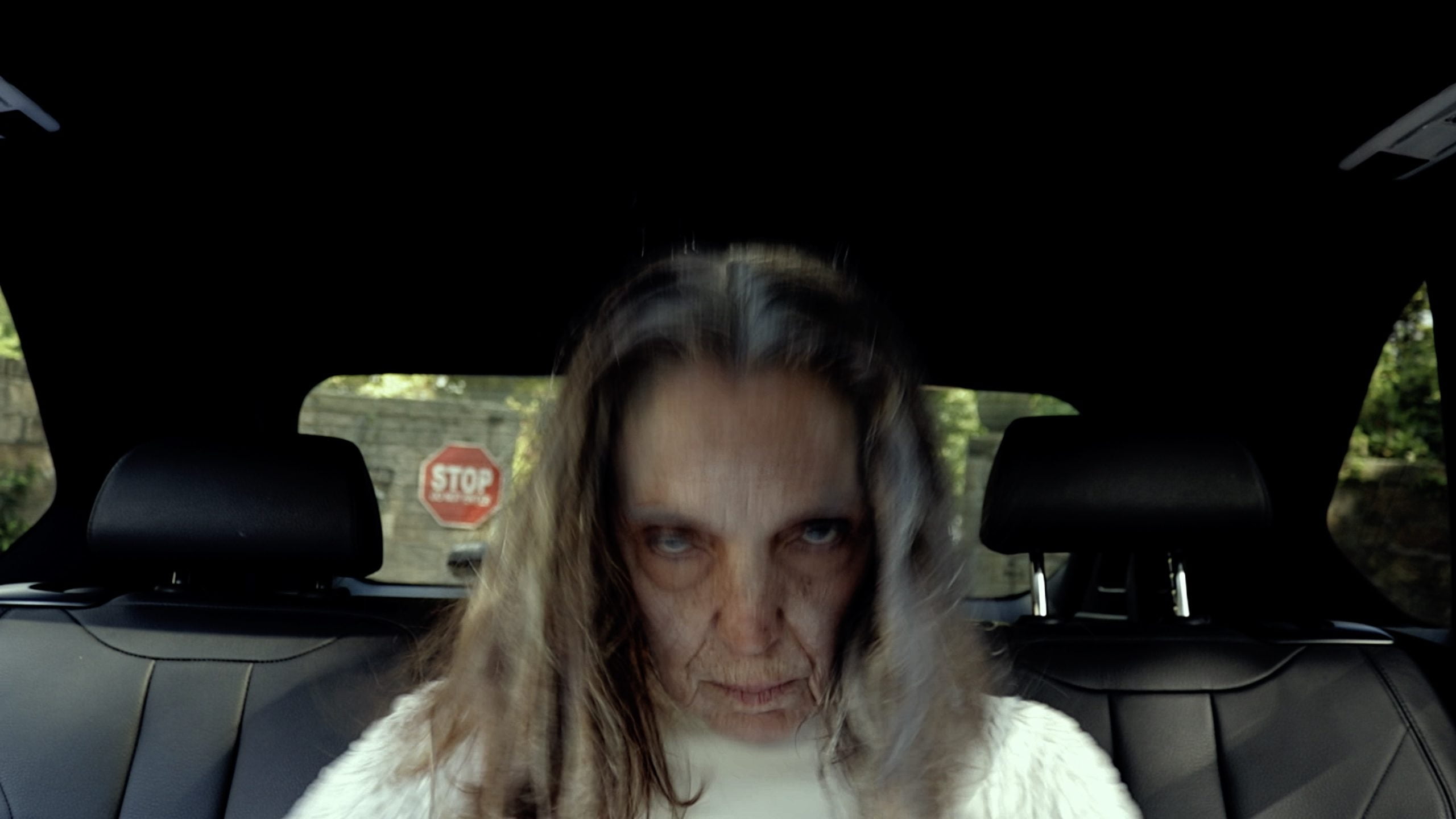 Shot of an old woman in the back of a car