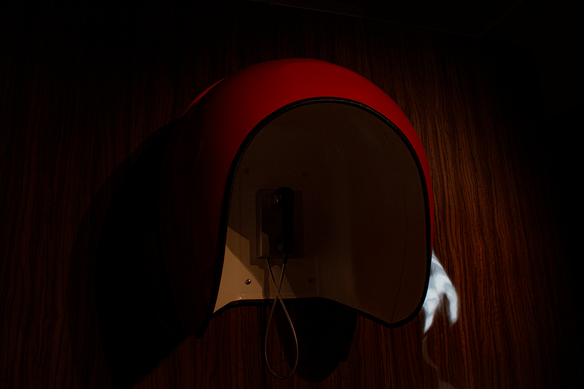 Dark moody image of an exhibition piece featuring a red 60s style phone.