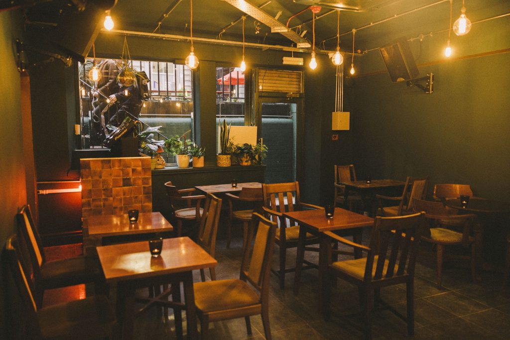 Photo of the inside of Holding Patterns – chairs, tables and lights