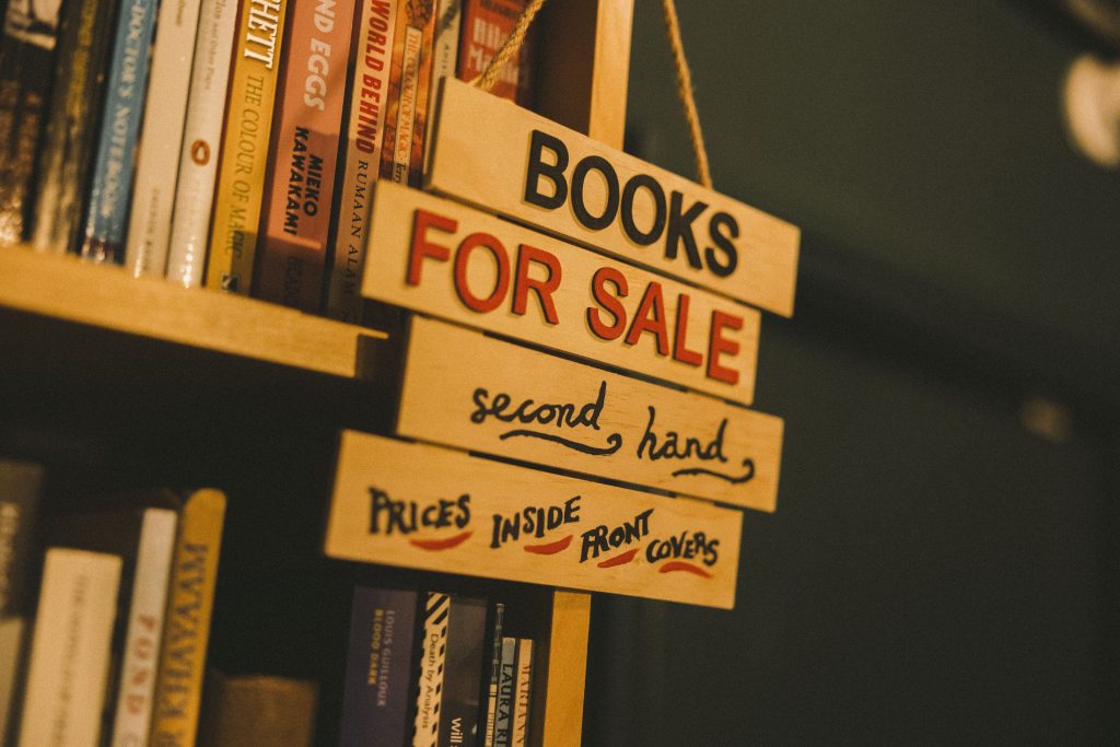 Picture of a sign reading 'books for sales - second hand, prices inside front covers' on a book shelf