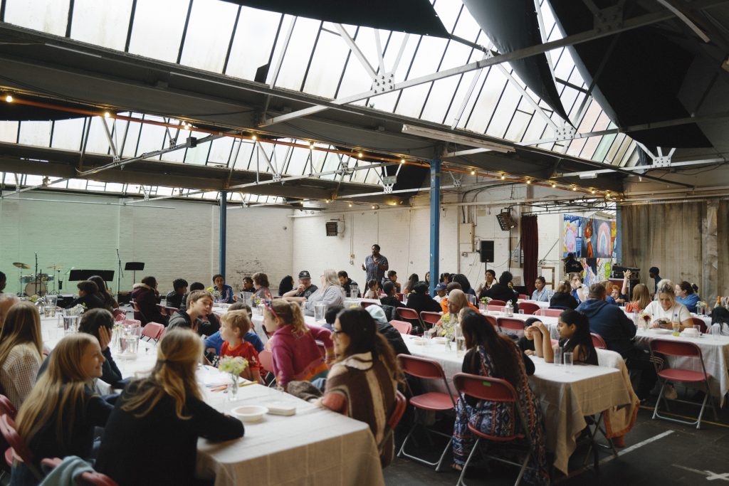 Picture of people sat on tables for a community meal at The Warehouse in Holbeck