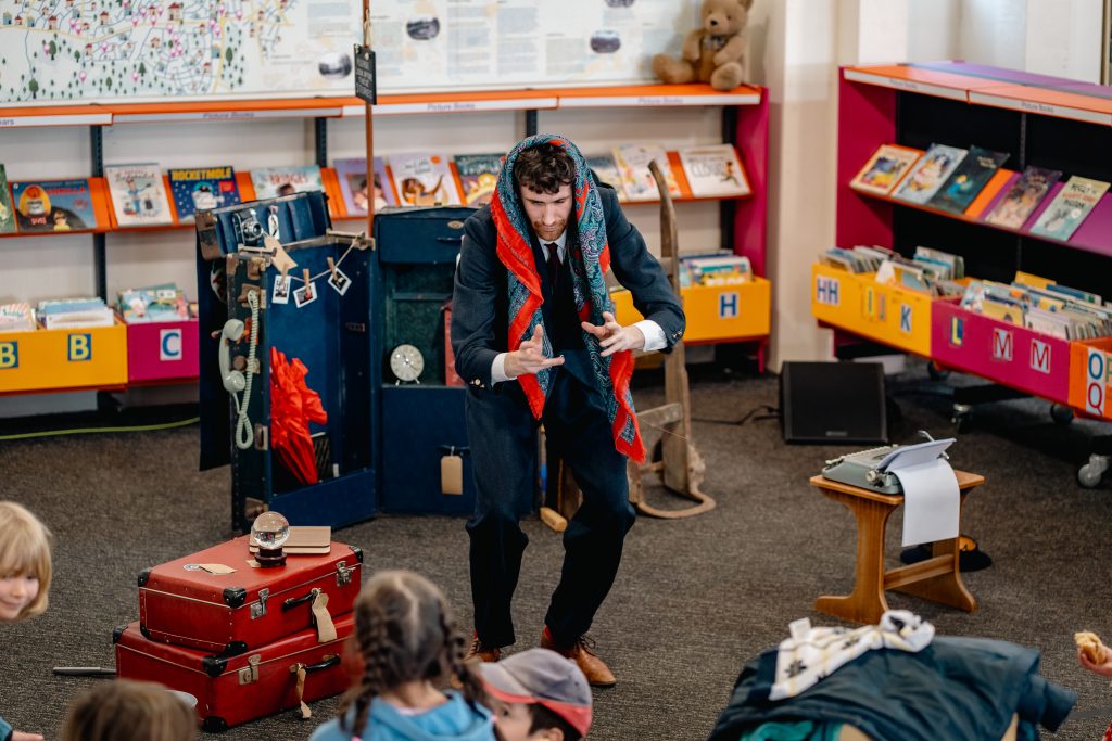 Image man performing The Lost Property Library to audience of excited children. 