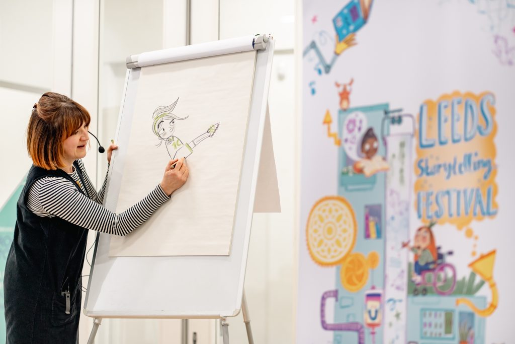 Image of woman drawing a children's illustration on a whiteboard. 